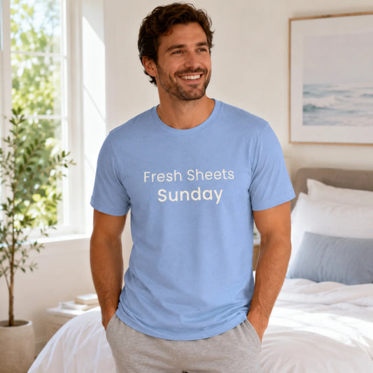 Male model wearing a heather carolina blue Fresh Sheets Sunday T-shirt in a relaxed, fresh morning lifestyle setting.