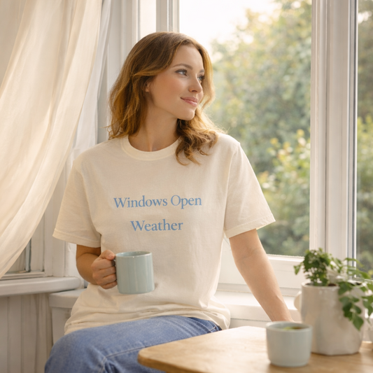 Woman wearing ivory Windows Open Weather Comfort Colors T-shirt sitting by an open window with morning sunlight lifestyle mockup
