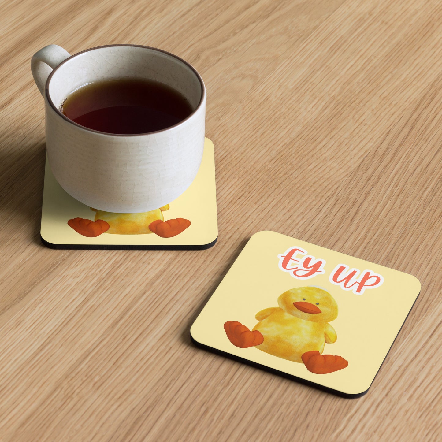 Ey Up Duck coaster on wooden table with a mug, cheerful Yorkshire-themed drinks coaster in use