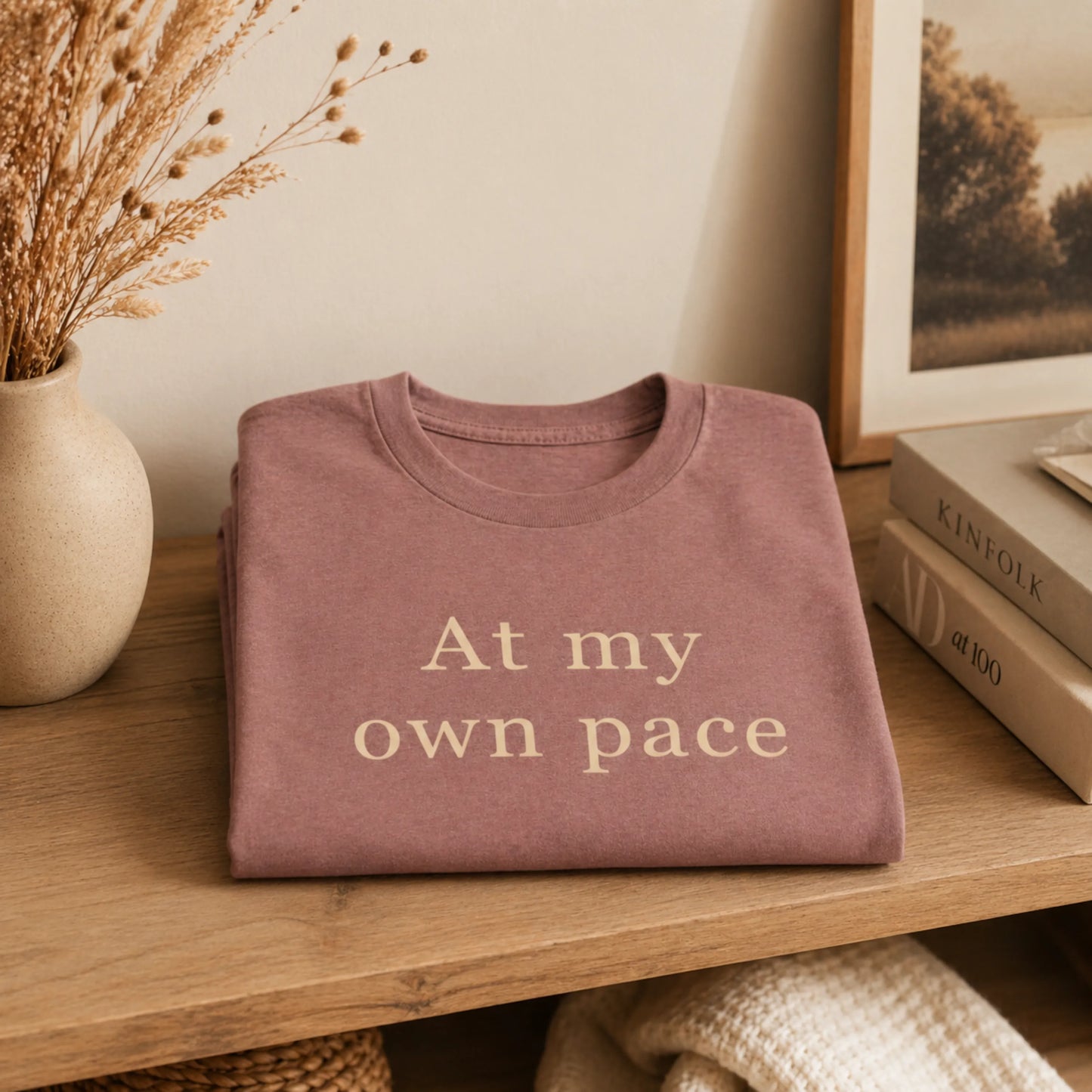 Folded At My Own Pace T-Shirt styled on a warm shelf with soft neutral home decor.