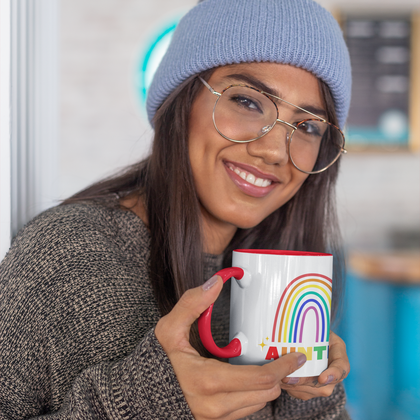 Woman smiling while holding Auntie rainbow ceramic mug with red interior