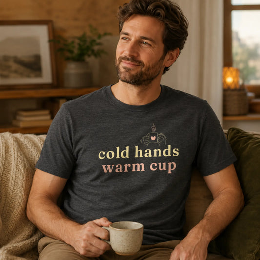 Male model wearing a dark grey heather Cold Hands Warm Cup T-shirt, styled in a warm casual setting with a cosy everyday feel.