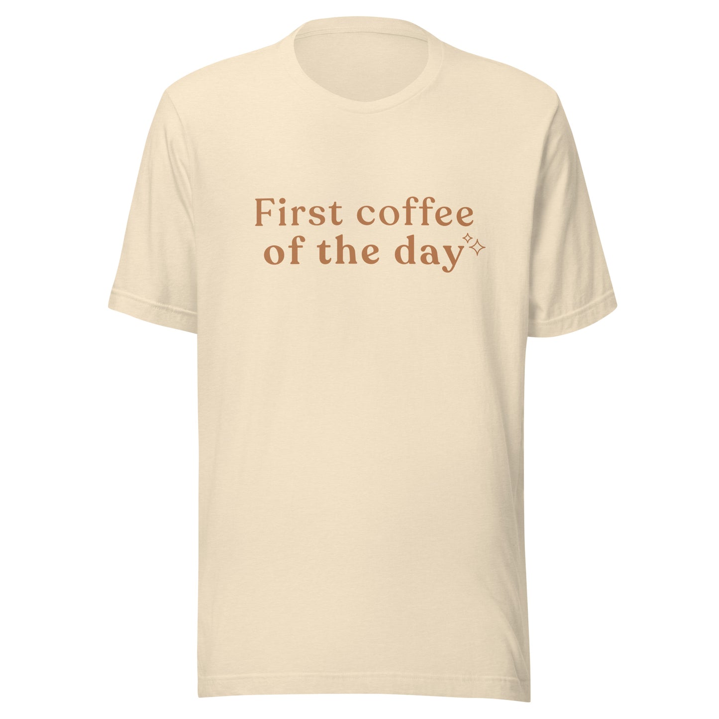 Cream First Coffee of the Day T-shirt flat lay showing warm brown text and small sparkle detail.