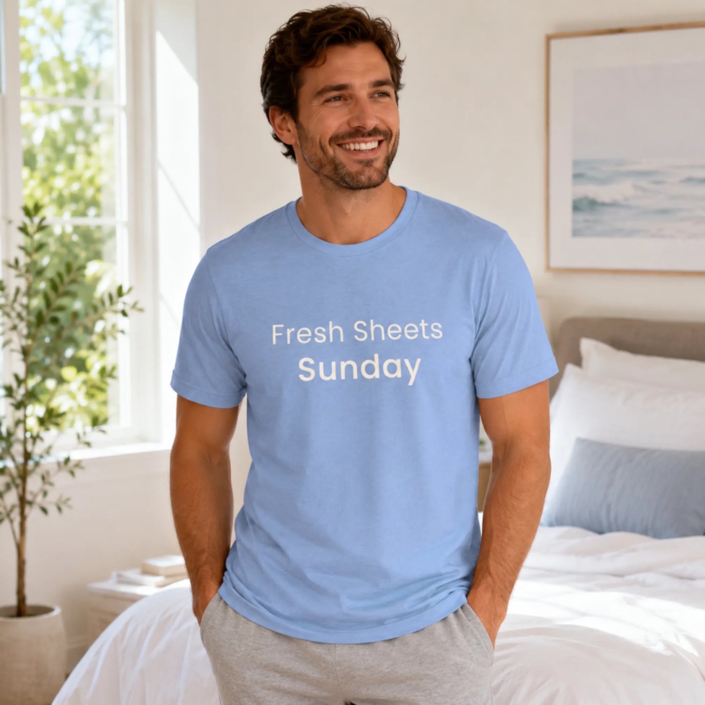 Male model wearing a heather carolina blue Fresh Sheets Sunday T-shirt in a relaxed, fresh morning lifestyle setting.