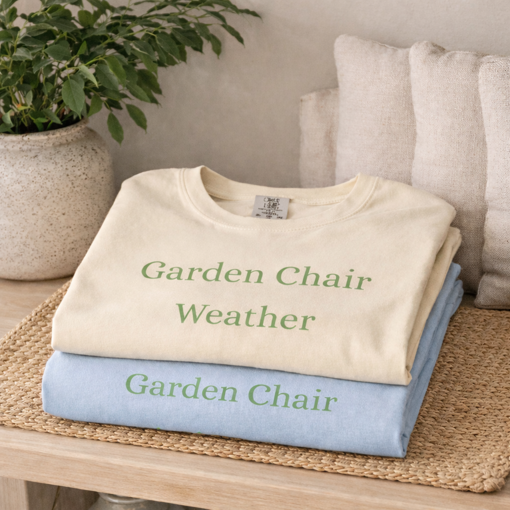 Folded Garden Chair Weather T-shirts in ivory and chambray stacked on a wooden shelf