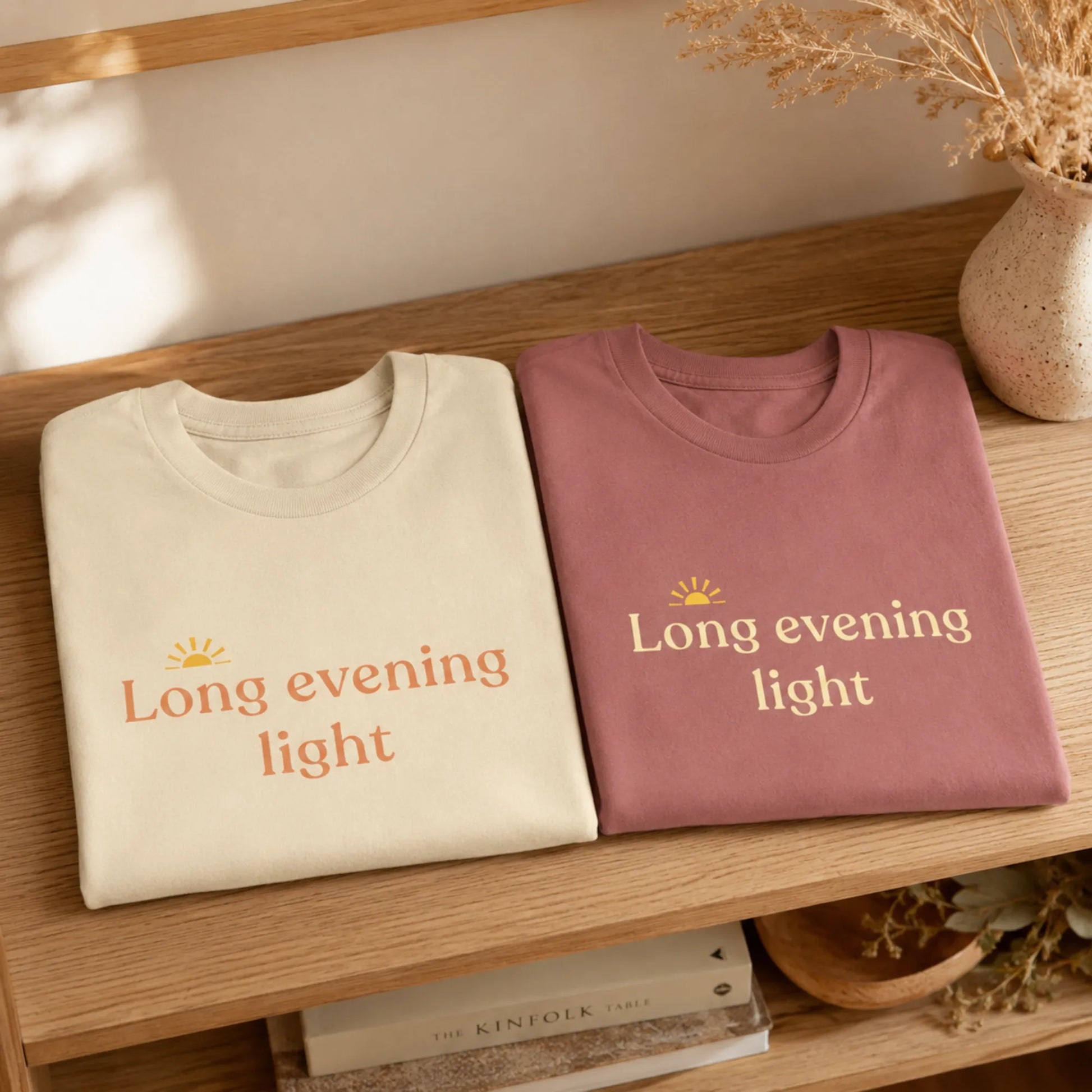 Folded Long Evening Light T-Shirts displayed on a warm wooden shelf with soft seasonal decor.