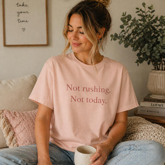 Woman wearing soft peach pink Not Rushing Not Today T-shirt in a calm indoor setting, relaxed slow living lifestyle