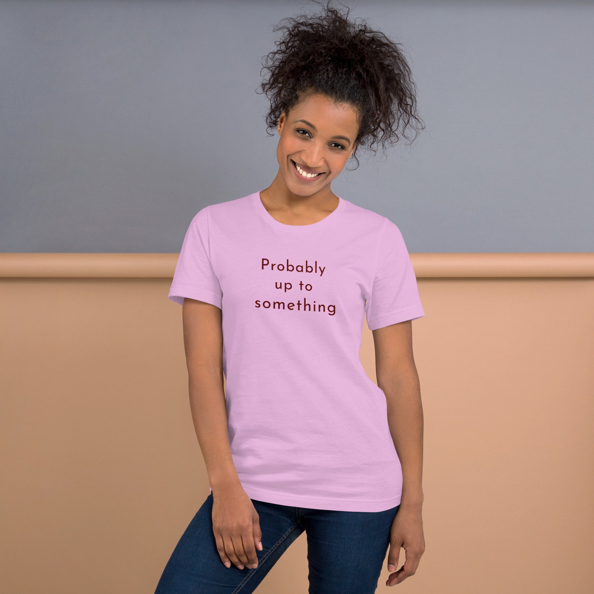 Woman wearing pink Probably Up To Something graphic tee with warm brown typography