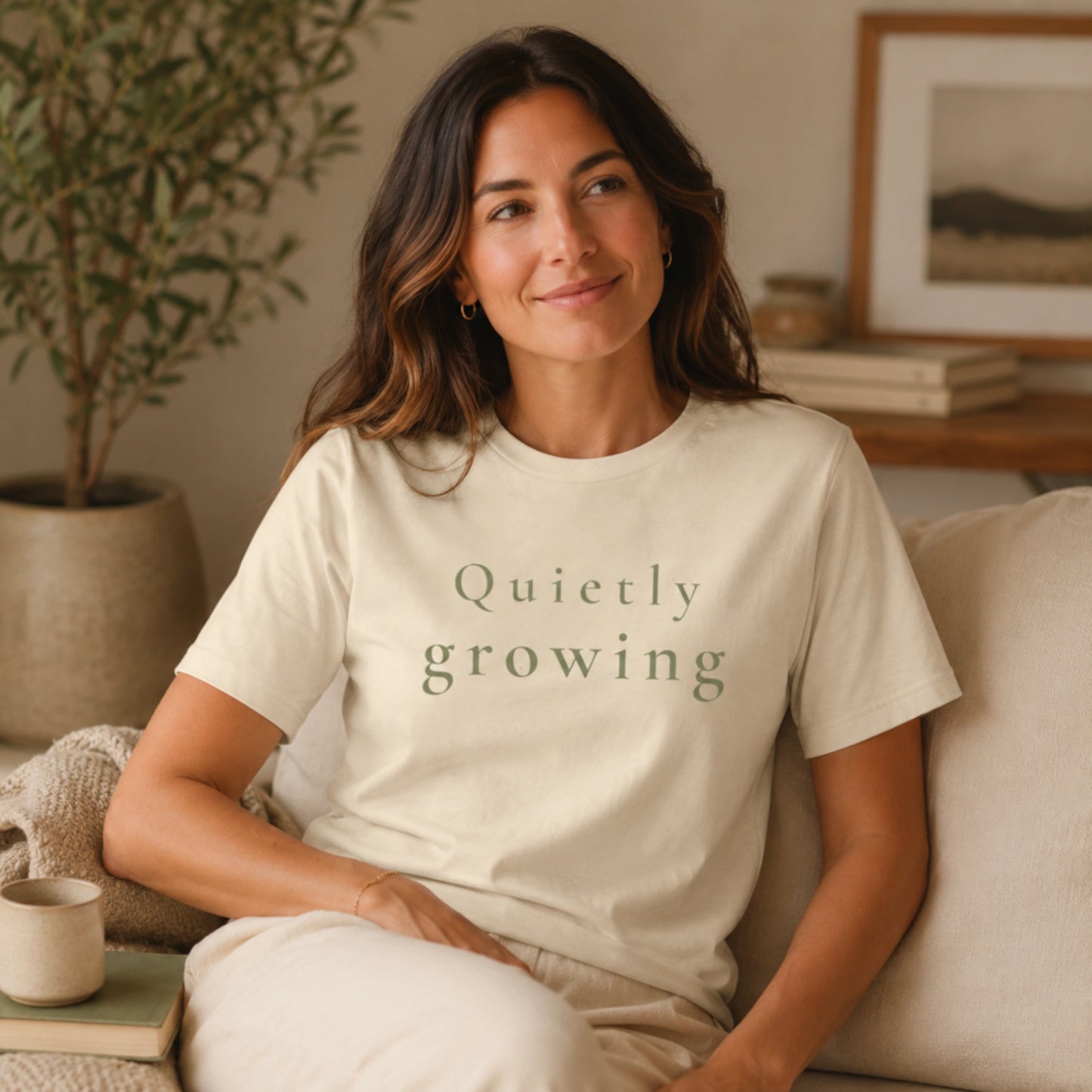 Female model wearing a Heather Natural Quietly Growing T-shirt in a calm, cosy indoor lifestyle setting.