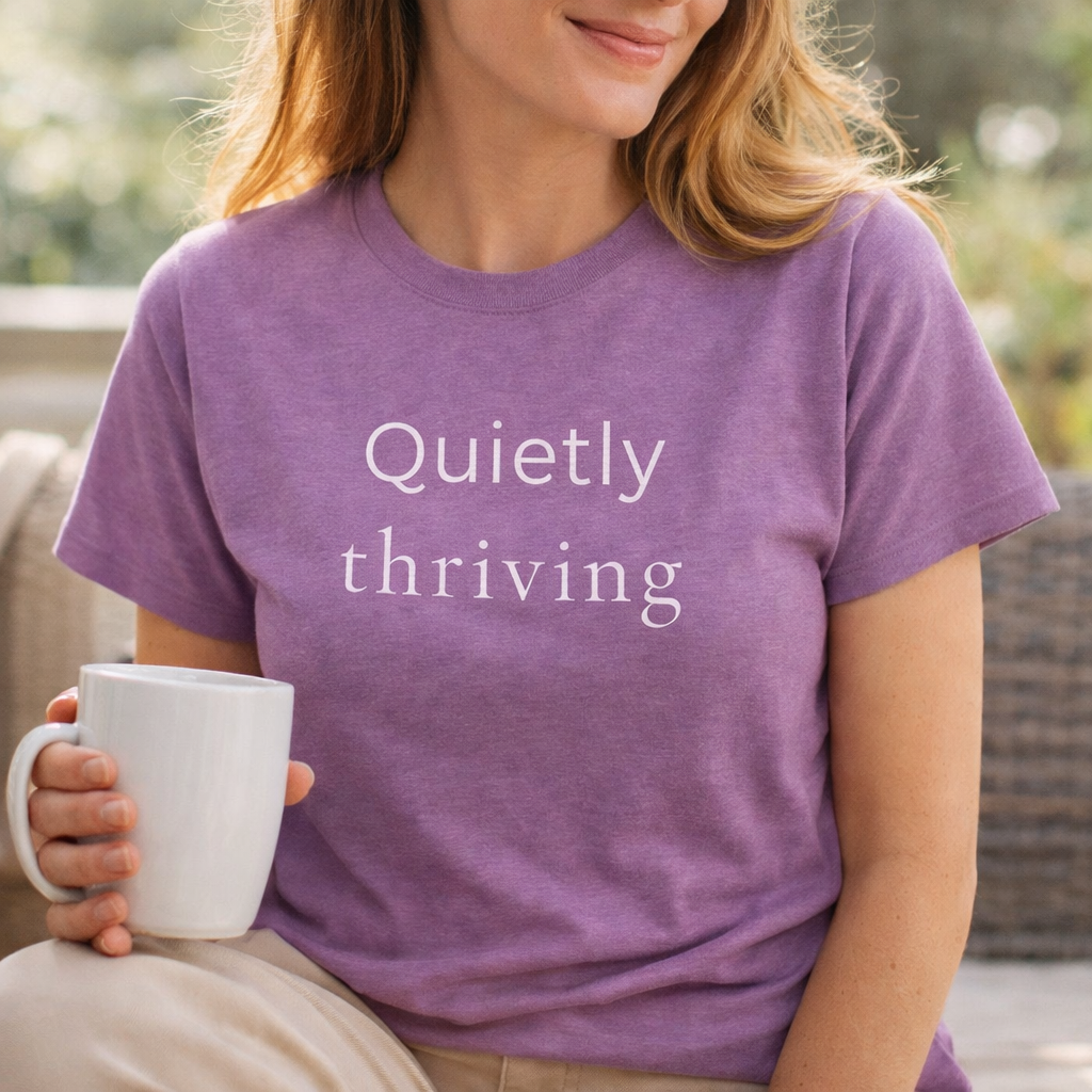 Woman wearing a heather purple Bella Canvas T-shirt with “Quietly thriving” text, relaxed lifestyle mockup holding a mug