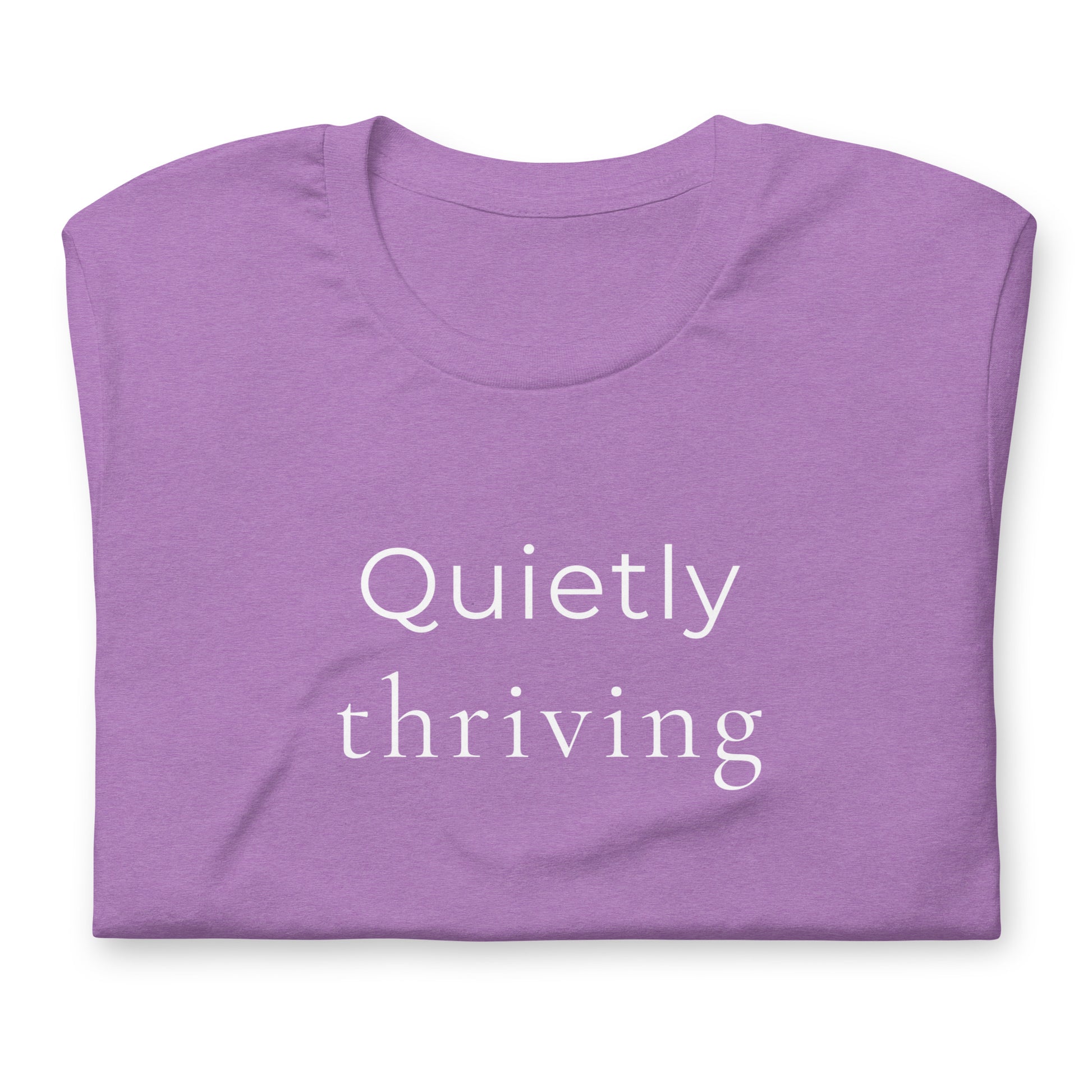 Folded heather purple “Quietly Thriving” T-shirt showing minimal typography design detail