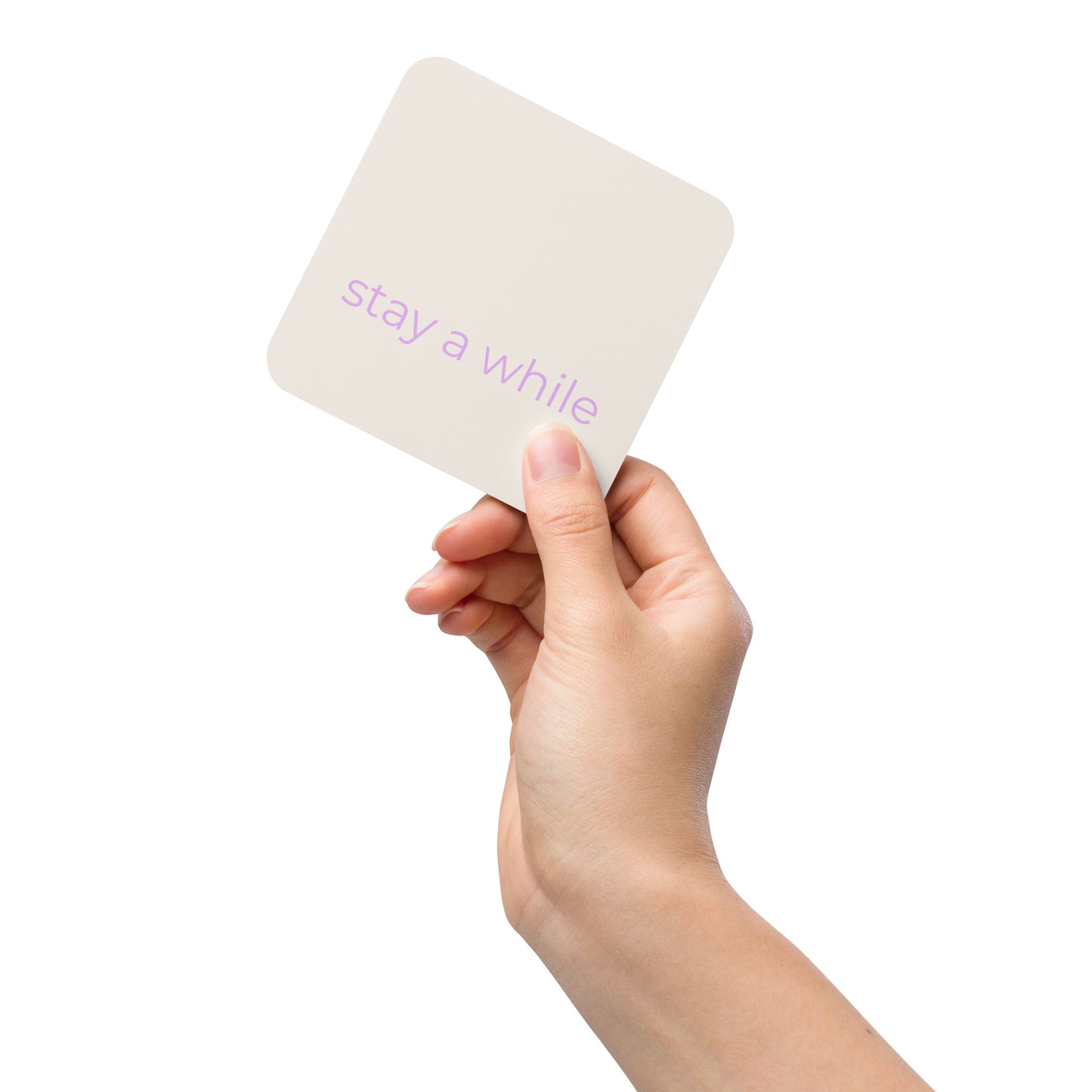 Hand holding a neutral coaster with “stay a while” text in soft purple against a clean background