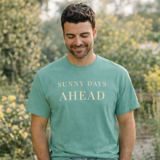 Man wearing a Comfort Colors t-shirt in seafoam with 'Sunny Days Ahead' text, standing outdoors