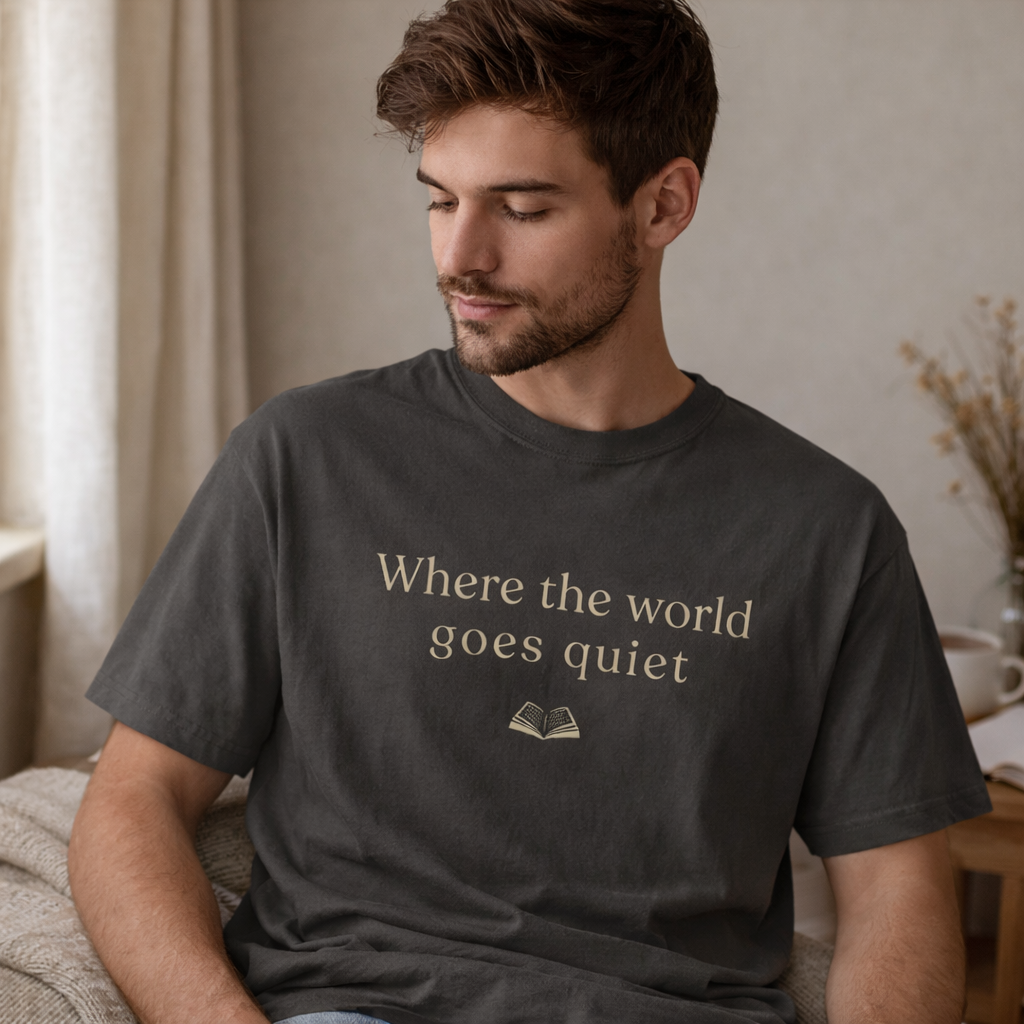 Man wearing pepper grey Comfort Colors T-shirt with “Where the world goes quiet” text, relaxed fit casual book lover outfit