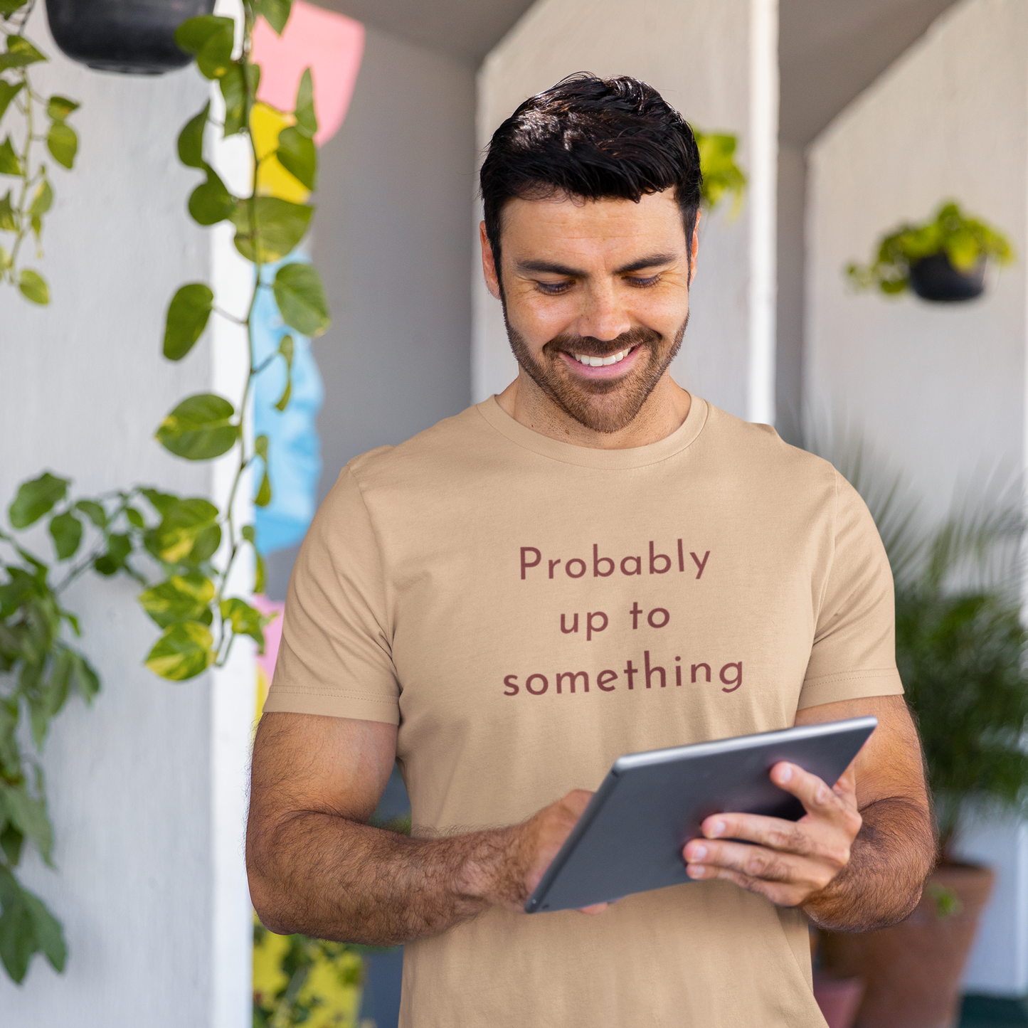 Man wearing tan Probably Up To Something graphic tee with warm brown typography