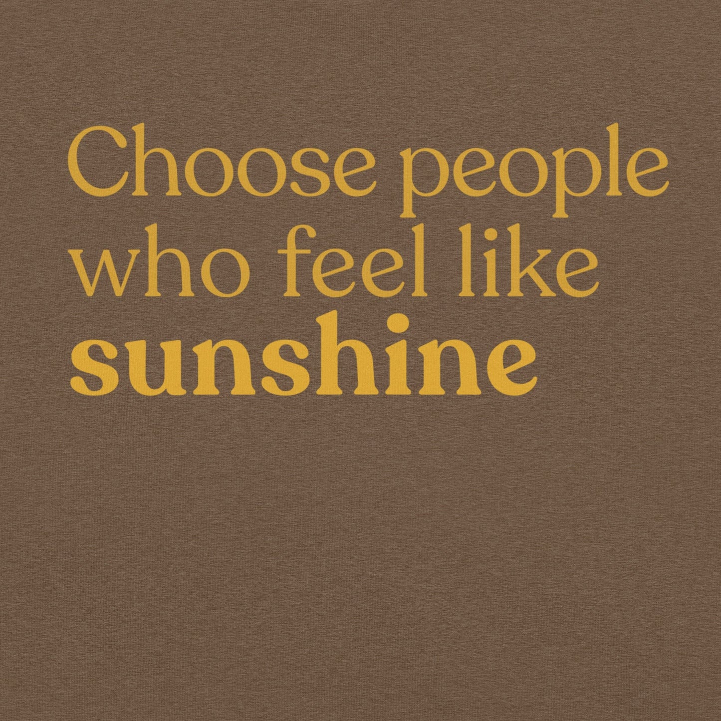 Close-up of the phrase “Choose people who feel like sunshine” printed in warm yellow text on a heather brown T-shirt