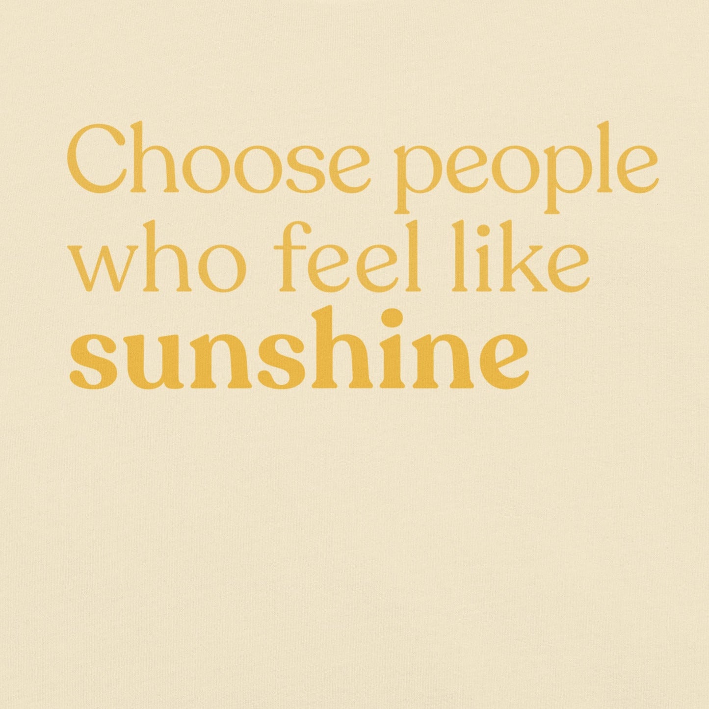 Close-up of the phrase “Choose people who feel like sunshine” printed in warm yellow text on a natural colour T-shirt