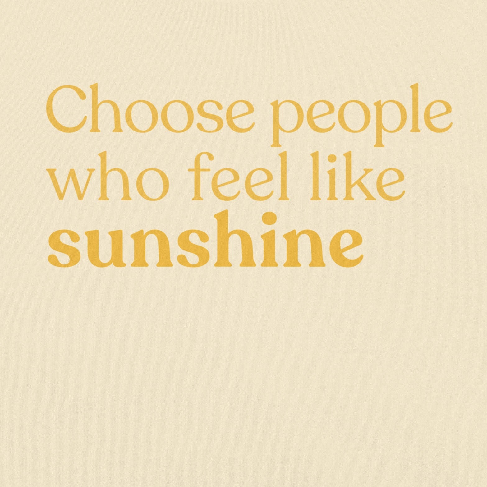 Close-up of the phrase “Choose people who feel like sunshine” printed in warm yellow text on a natural colour T-shirt
